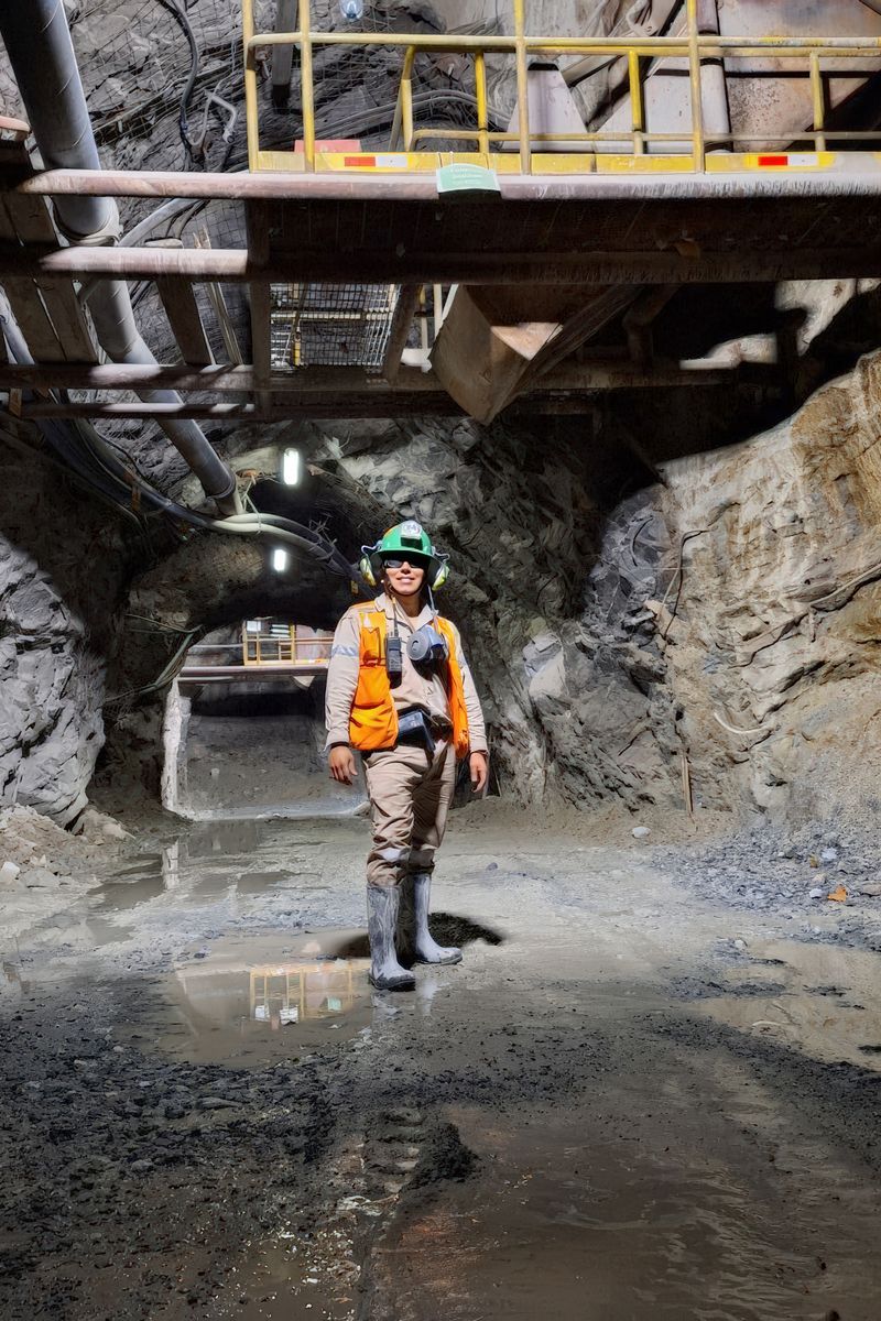 Engineer standing in an illuminated underground mine tunnel, showcasing mining safety gear and modern infrastructure.